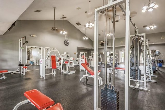 gym featuring high vaulted ceiling and ceiling fan with notable chandelier