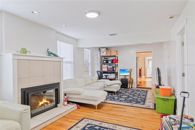 living room with a tile fireplace and hardwood / wood-style flooring