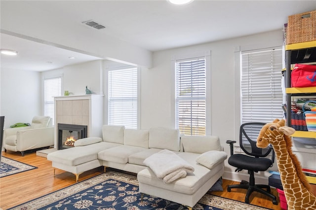 living room with a tile fireplace, plenty of natural light, and hardwood / wood-style flooring