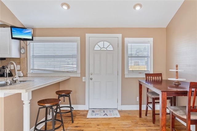 interior space with sink, lofted ceiling, and light wood-type flooring