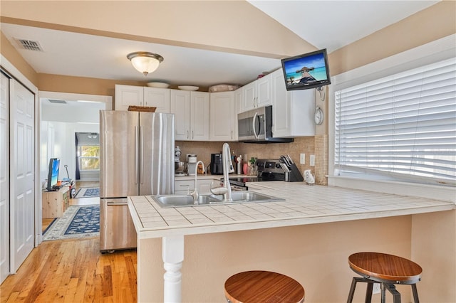 kitchen with a breakfast bar, kitchen peninsula, stainless steel appliances, and white cabinets