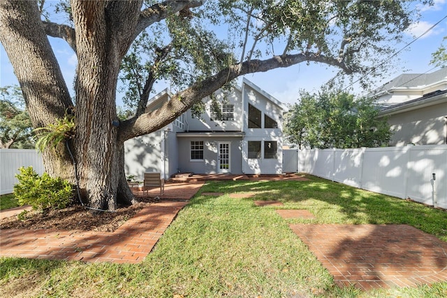 mid-century modern home with a fenced backyard, a patio area, and a front lawn