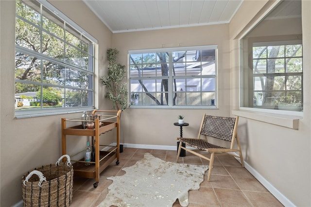 sunroom featuring tile patterned flooring, crown molding, and baseboards