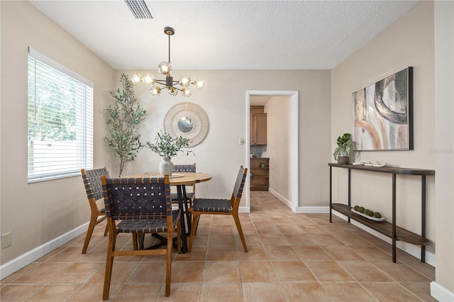 dining room with baseboards, a textured ceiling, visible vents, and a chandelier