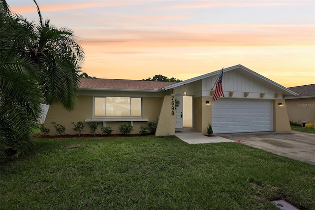 ranch-style house with a garage and a lawn