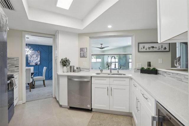 kitchen with tasteful backsplash, sink, white cabinets, and stainless steel dishwasher