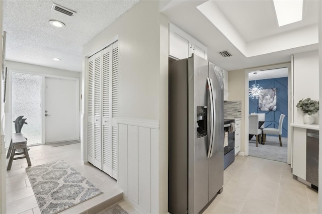 corridor featuring light tile patterned floors, a textured ceiling, and a chandelier