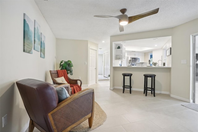 sitting room with ceiling fan, sink, and a textured ceiling