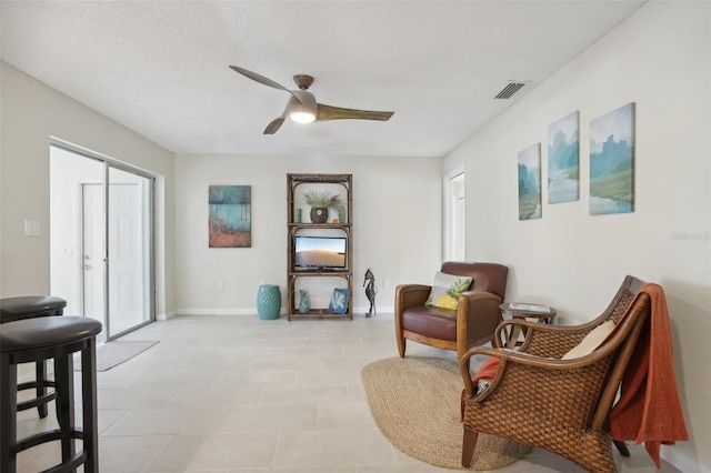 sitting room with ceiling fan and a textured ceiling