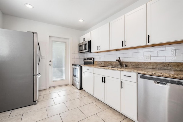 kitchen with appliances with stainless steel finishes, backsplash, sink, stone countertops, and white cabinetry