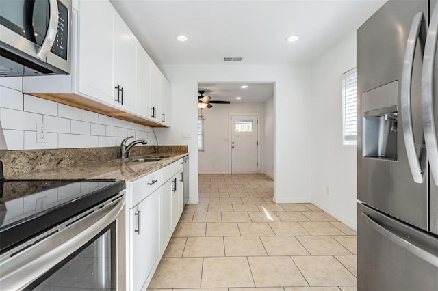 kitchen with white cabinets, appliances with stainless steel finishes, dark stone counters, and sink