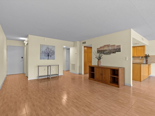 unfurnished living room with a textured ceiling and sink