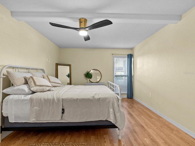 bedroom with ceiling fan, beam ceiling, and light hardwood / wood-style flooring