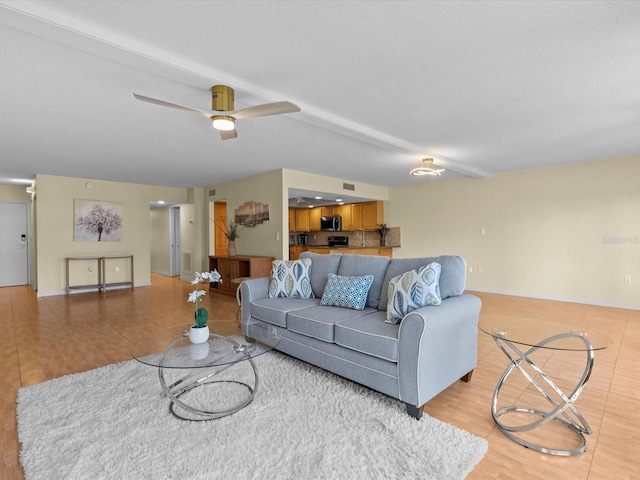 living room featuring ceiling fan, light wood-type flooring, and a textured ceiling