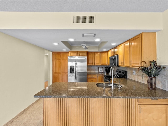 kitchen with decorative backsplash, a raised ceiling, kitchen peninsula, and stainless steel appliances