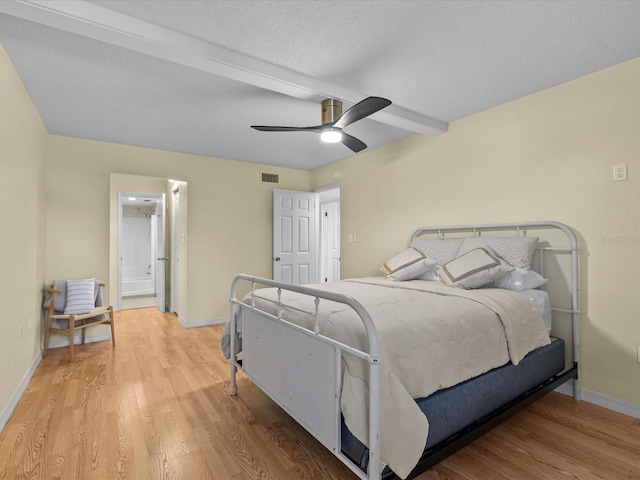 bedroom with ceiling fan, beam ceiling, light wood-type flooring, and a textured ceiling