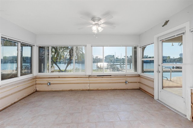 unfurnished sunroom with ceiling fan and a water view