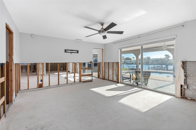 empty room with concrete flooring, ceiling fan, and a water view