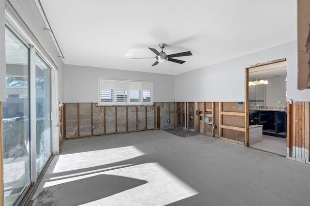 empty room with ceiling fan with notable chandelier and concrete flooring