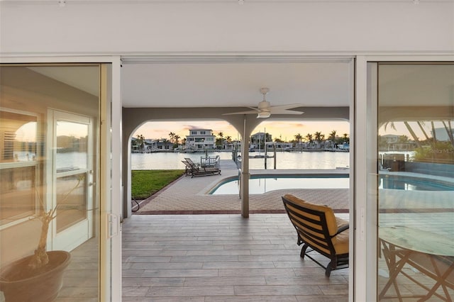 doorway with ceiling fan, a water view, and hardwood / wood-style flooring