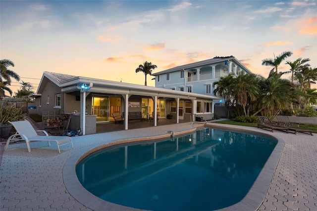 pool at dusk with a patio area