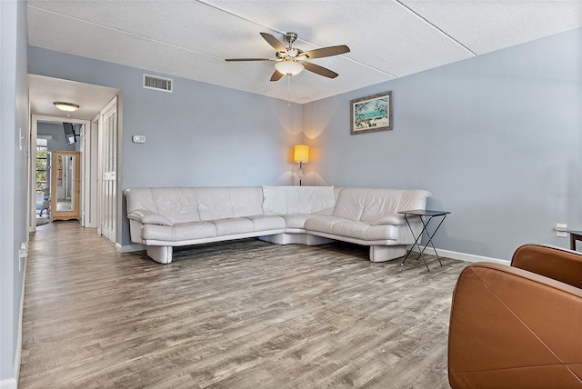 living room with hardwood / wood-style floors, ceiling fan, and a textured ceiling