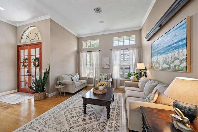 living room with french doors, a towering ceiling, light hardwood / wood-style flooring, and ornamental molding