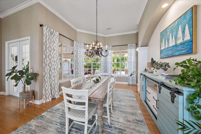 dining room with light hardwood / wood-style flooring, an inviting chandelier, and crown molding