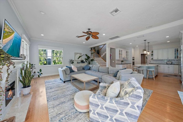 living room with ceiling fan, sink, light wood-type flooring, and ornamental molding