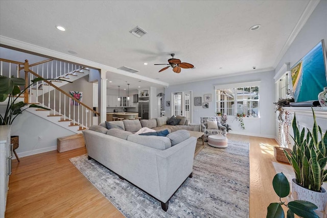 living room featuring ceiling fan, crown molding, and light hardwood / wood-style flooring