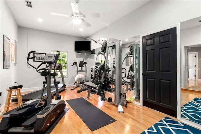 exercise room with ceiling fan, vaulted ceiling, and hardwood / wood-style flooring