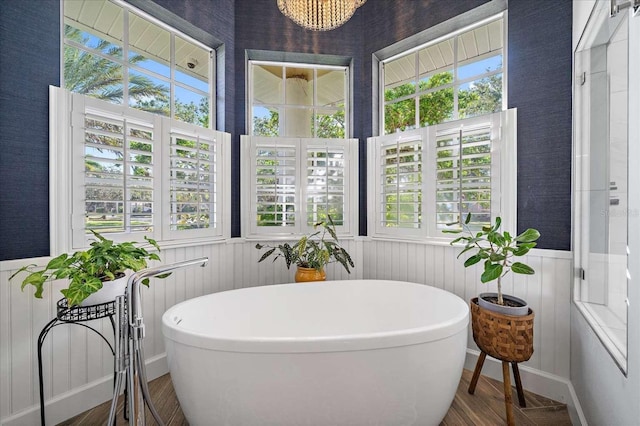 bathroom with wood-type flooring, plenty of natural light, and a bathtub