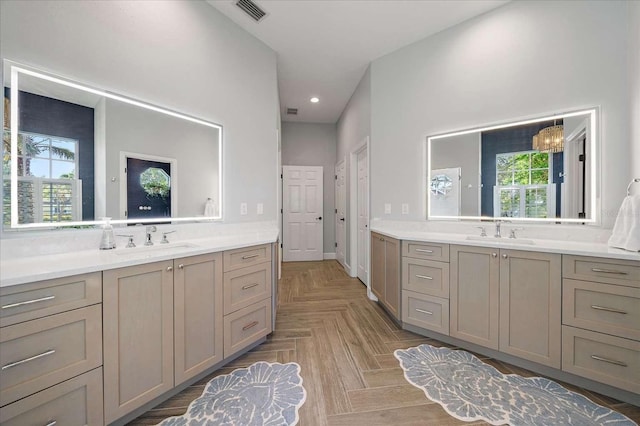 bathroom with an inviting chandelier, vanity, and parquet flooring