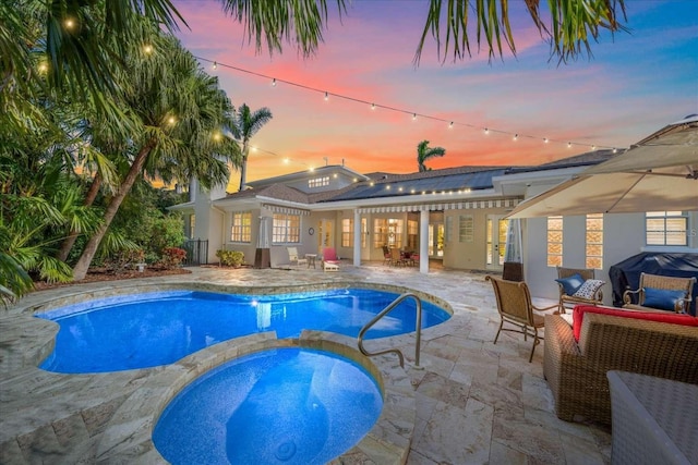 pool at dusk featuring a patio area, an in ground hot tub, and area for grilling