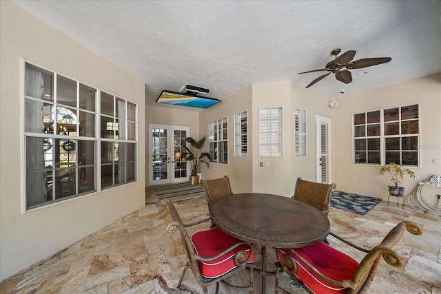 dining area with french doors, a textured ceiling, and ceiling fan