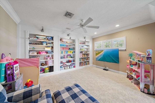 recreation room with carpet, built in shelves, ceiling fan, ornamental molding, and a textured ceiling