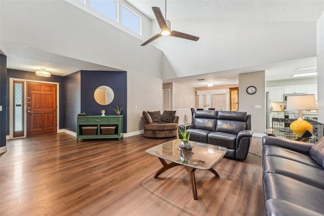 living room with high vaulted ceiling, ceiling fan, and dark wood-type flooring