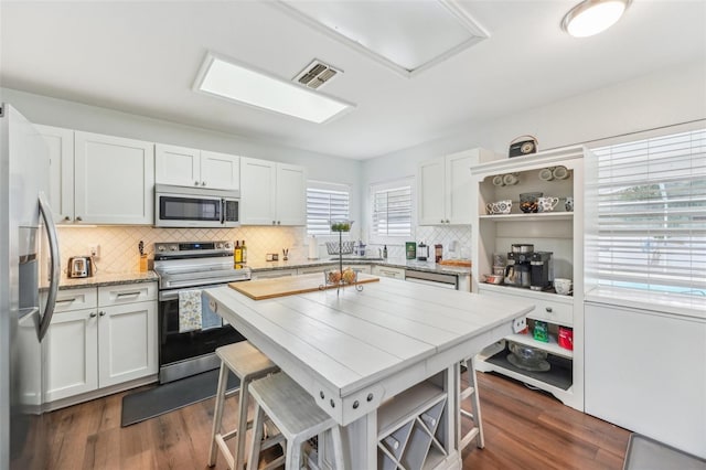 kitchen with white cabinets, a kitchen breakfast bar, and appliances with stainless steel finishes