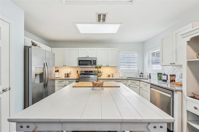 kitchen with white cabinets, appliances with stainless steel finishes, and tile counters