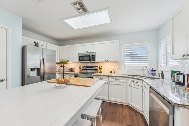 kitchen featuring sink, stainless steel appliances, dark hardwood / wood-style floors, a breakfast bar, and white cabinets