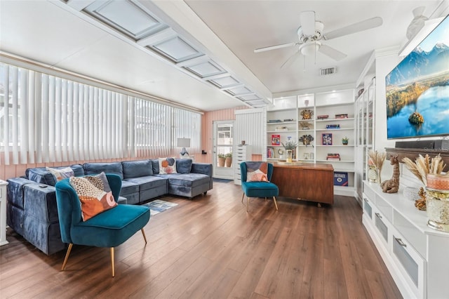 living room featuring ceiling fan, dark hardwood / wood-style flooring, and built in shelves