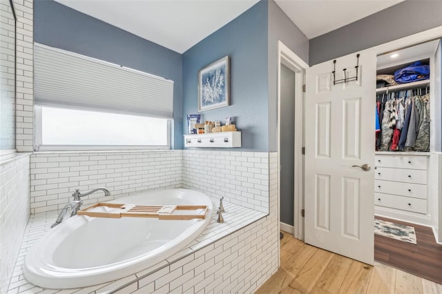 bathroom featuring tiled bath and wood-type flooring