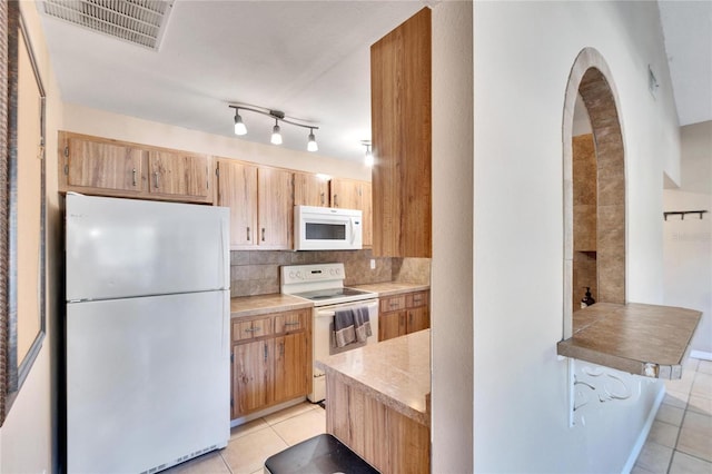 kitchen with light tile patterned flooring, white appliances, and tasteful backsplash