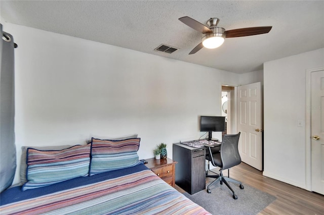 bedroom featuring hardwood / wood-style flooring, ceiling fan, and a textured ceiling