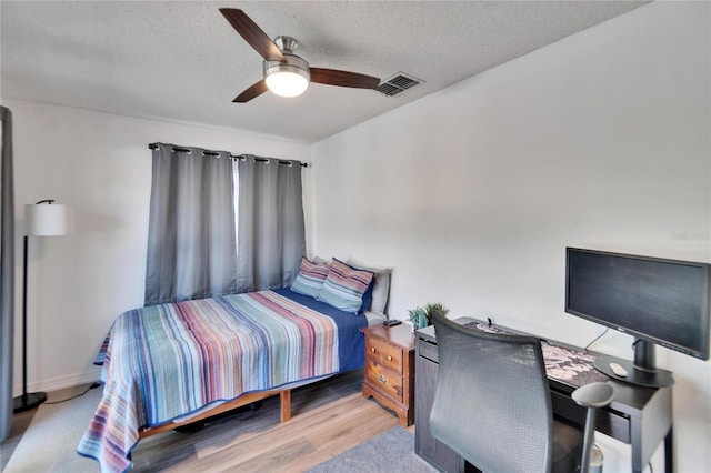 bedroom with ceiling fan, a textured ceiling, and light hardwood / wood-style flooring