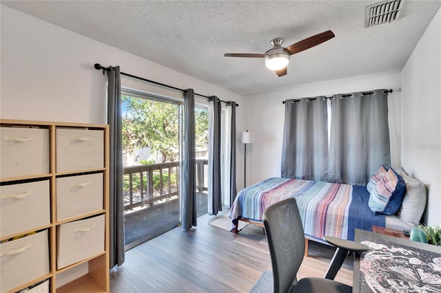 bedroom featuring access to outside, ceiling fan, light hardwood / wood-style floors, and a textured ceiling