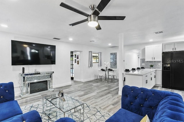 living room featuring ceiling fan and light hardwood / wood-style floors