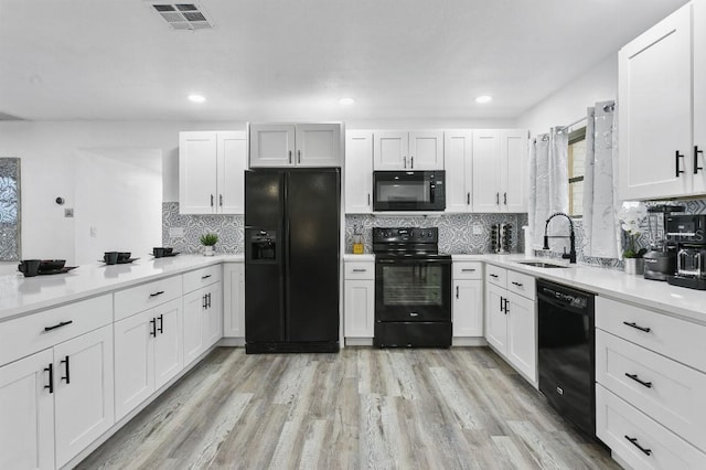 kitchen with black appliances, white cabinets, and sink