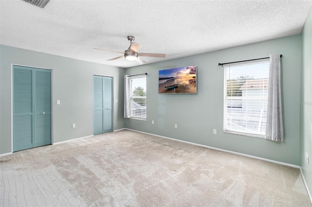 1600 Gray Bark Dr, Oldsmar, FL 34677 - unfurnished bedroom with visible vents, two closets, baseboards, a textured ceiling, and carpet