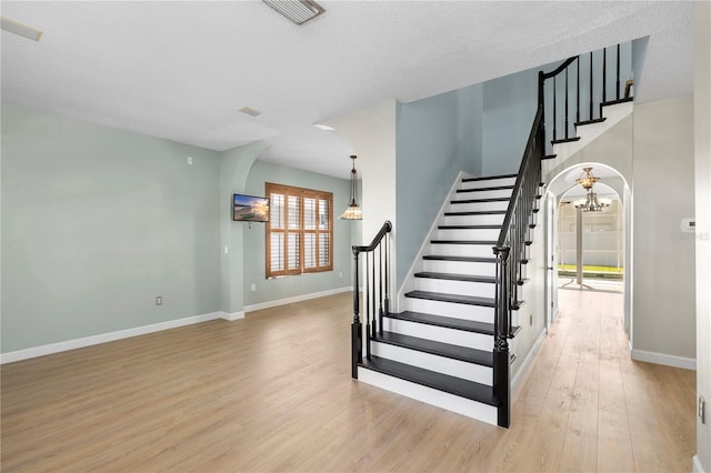 1600 Gray Bark Dr, Oldsmar, FL 34677 - stairs featuring visible vents, wood finished floors, baseboards, a textured ceiling, and a chandelier